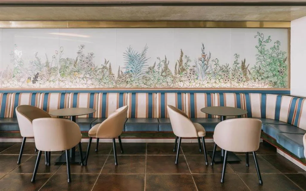 Angolo lounge con divani a righe, sedie e decorazione floreale a parete