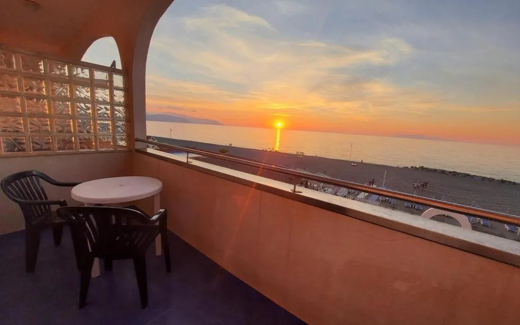 Balcone con tavolino e vista sul mare al tramonto