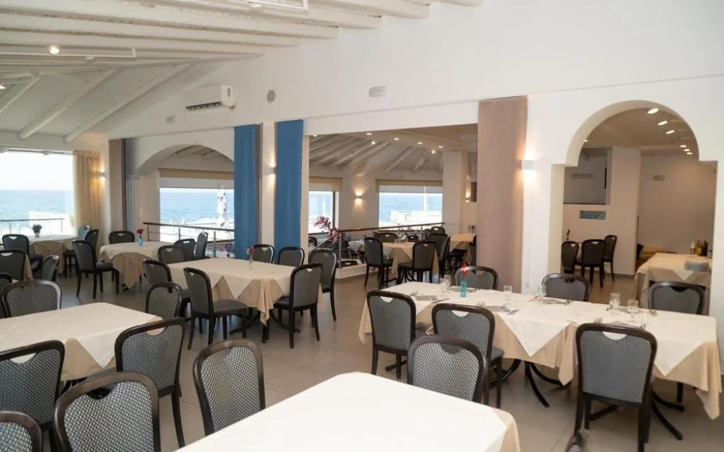 Sala ristorante con tavoli apparecchiati e vista mare