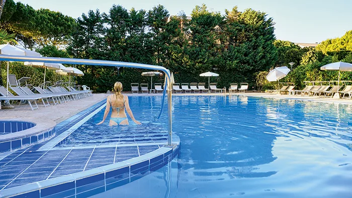 Piscina esterna con lettini, ombrelloni e vegetazione circostante
