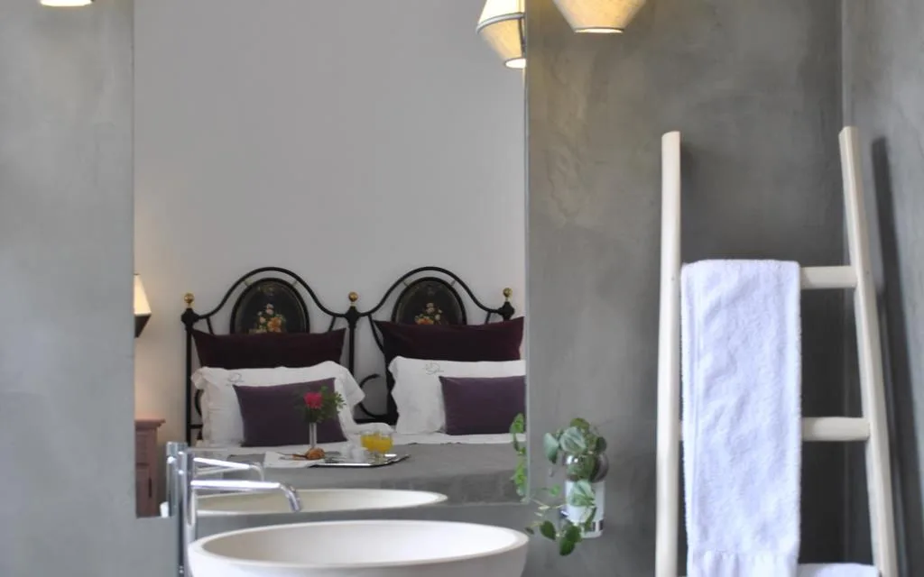 Dettaglio camera con letto in ferro battuto e lavabi in primo piano