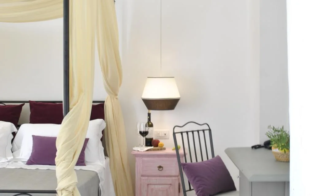 Camera con letto a baldacchino, comodino rosa e cuscini viola