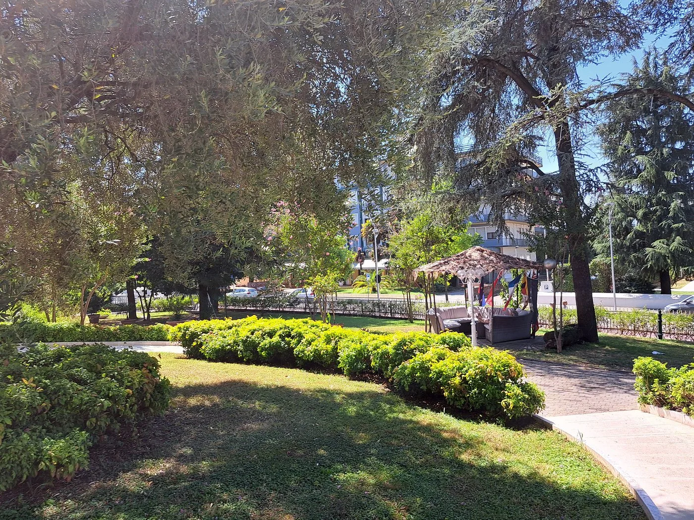 Giardino dell'hotel con alberi, siepi curate e area lounge esterna