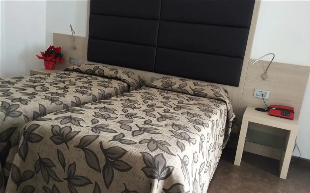 Camera con letto matrimoniale, testiera imbottita e comodino con telefono rosso