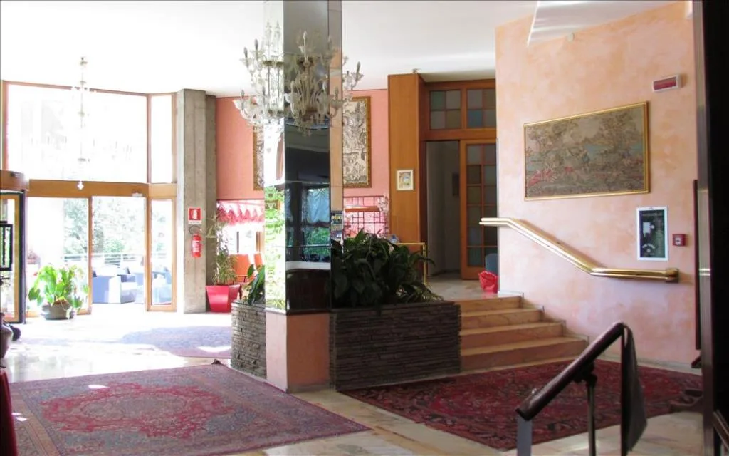 Ingresso dell'hotel con lampadario in vetro, tappeti e scalinata