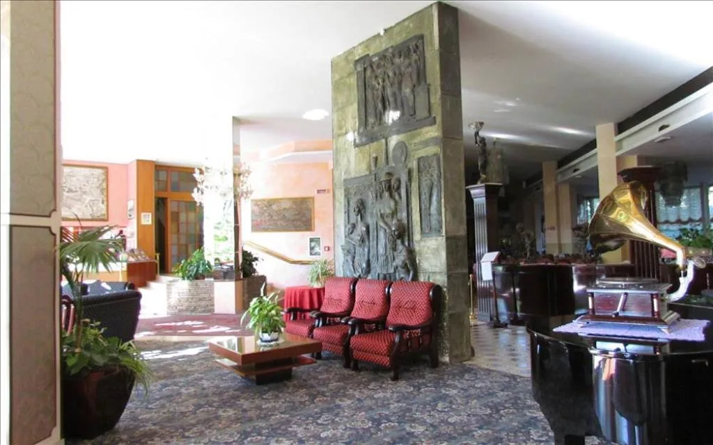 Hall dell'hotel con bassorilievi scultorei, grammofono e poltrone rosse