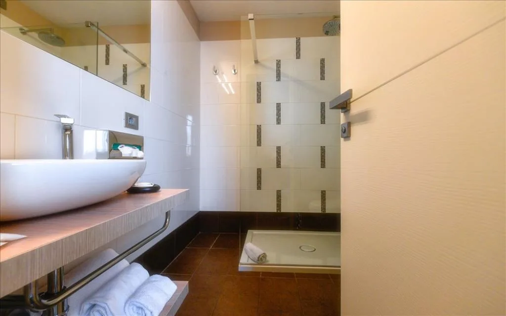 Bagno moderno con lavabo a bacinella, doccia e asciugamani