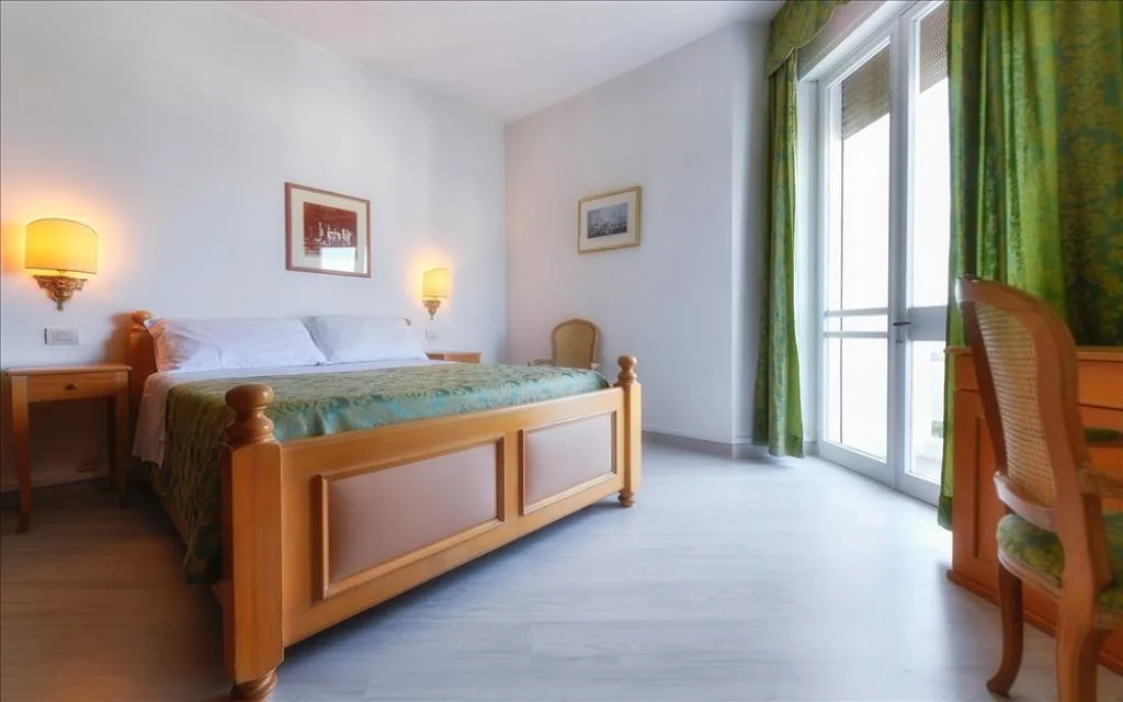 Camera luminosa con letto in legno, tende verdi e ampia finestra