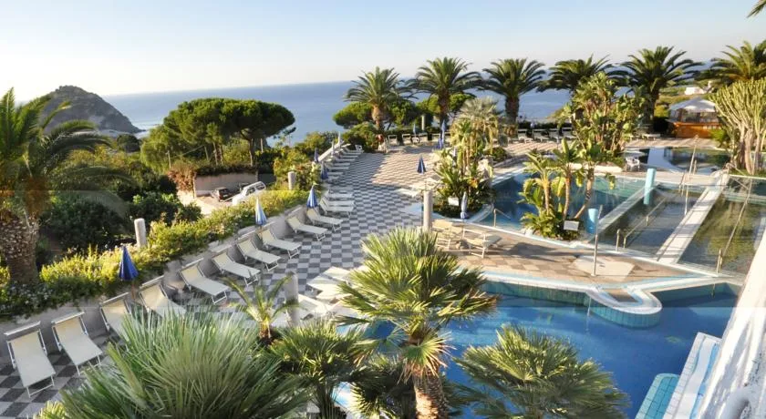 Area piscine termali con lettini, palme e vista mare