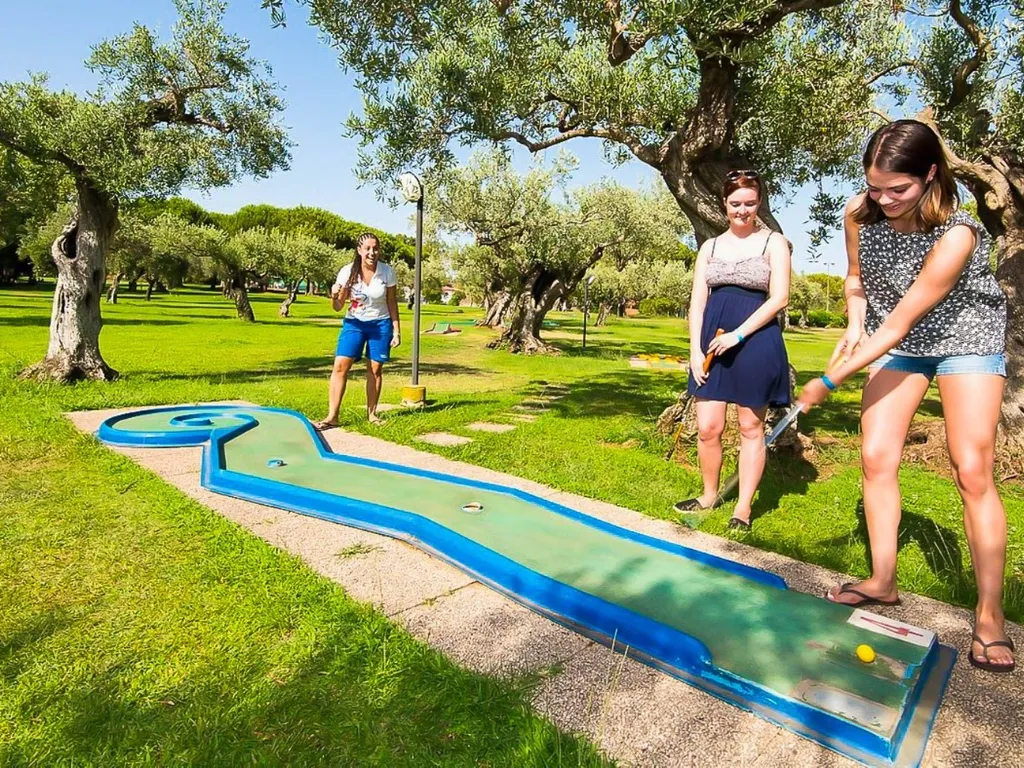 Ragazze giocano a minigolf tra gli ulivi del parco