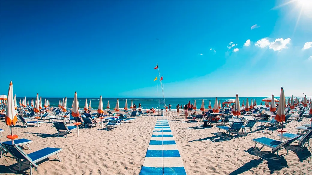 Spiaggia attrezzata con lettini, ombrelloni e passatoia verso il mare