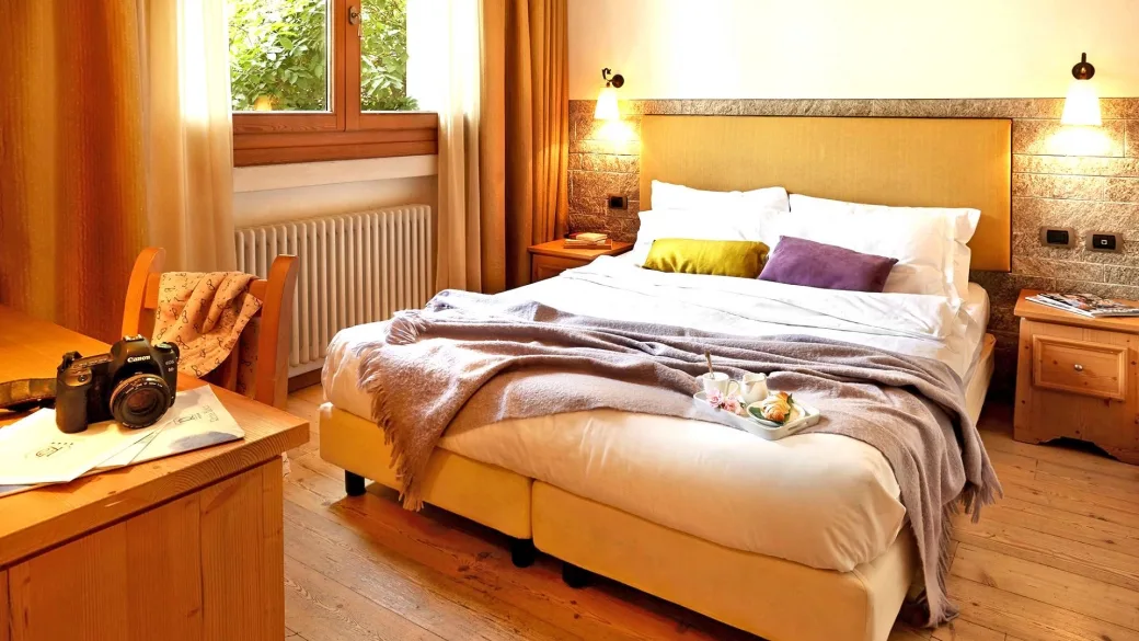 Camera matrimoniale con testiera in pietra, finestra e colazione servita sul letto