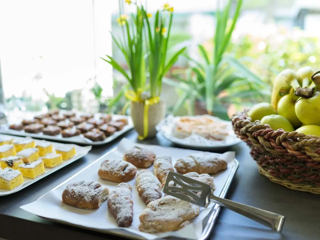 Buffet di colazione con dolci, pasticcini e cesto di frutta fresca vicino alla finestra