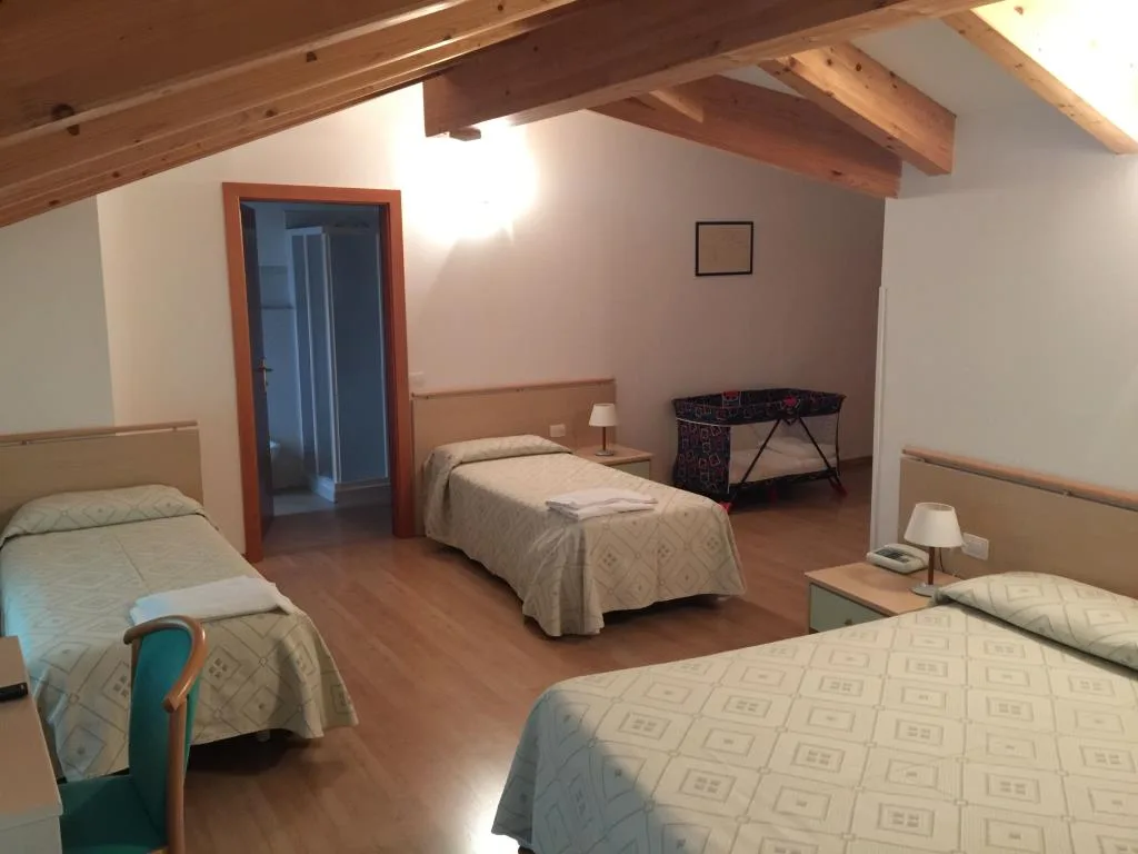 Camera familiare mansardata con travi in legno a vista, letti singoli, letto matrimoniale e culla