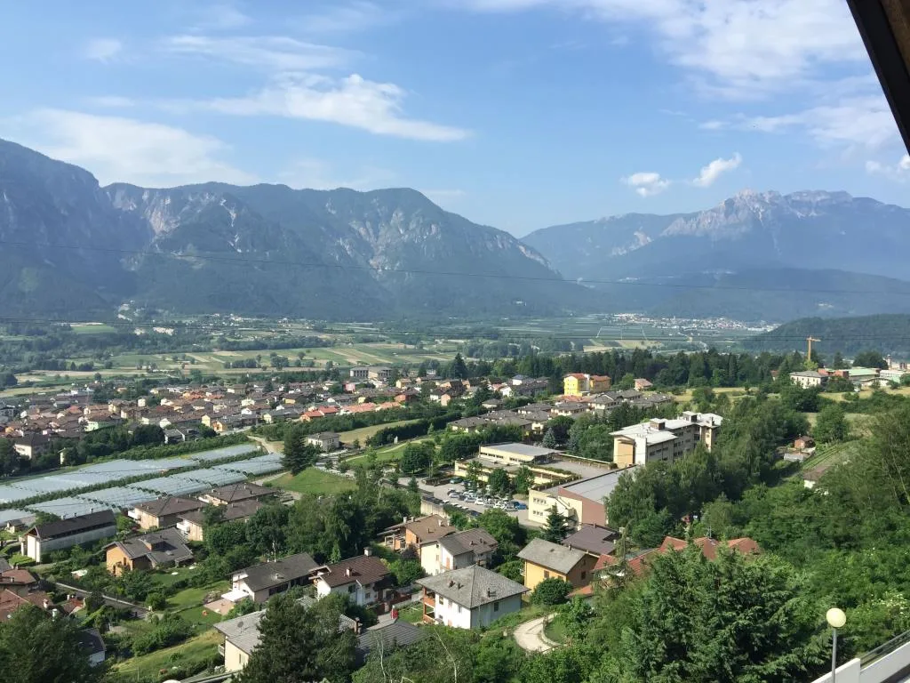 Vista panoramica sulla valle con paese, campi coltivati e montagne all'orizzonte