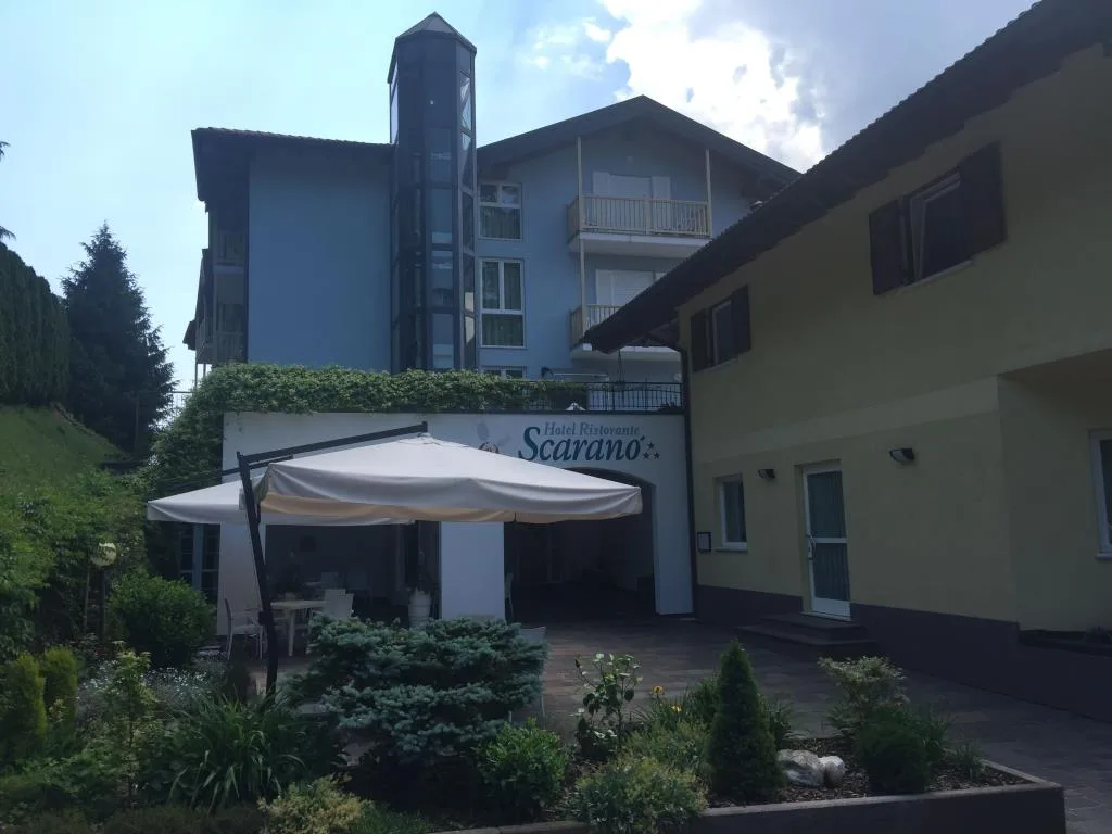 Vista esterna dell'Hotel Scarano con gazebo bianco, giardino e struttura azzurra
