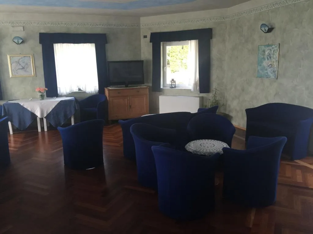 Sala soggiorno con poltrone blu, televisore, decorazioni a parete e finestre luminose