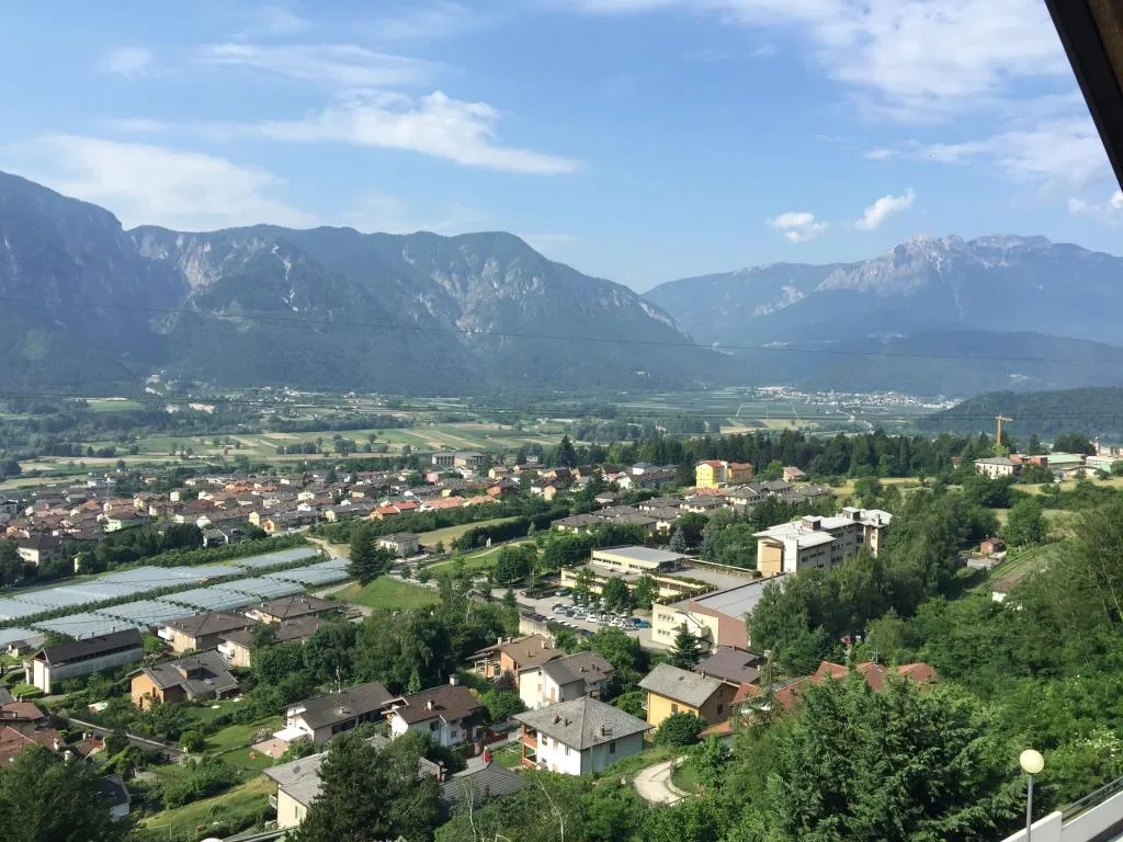 Panorama sulla valle con paese, campi verdi e catena montuosa sullo sfondo