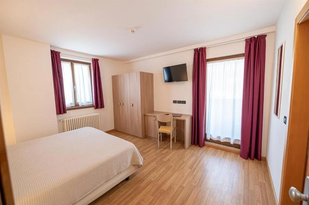 Camera luminosa con letto, armadio in legno e tende bordeaux