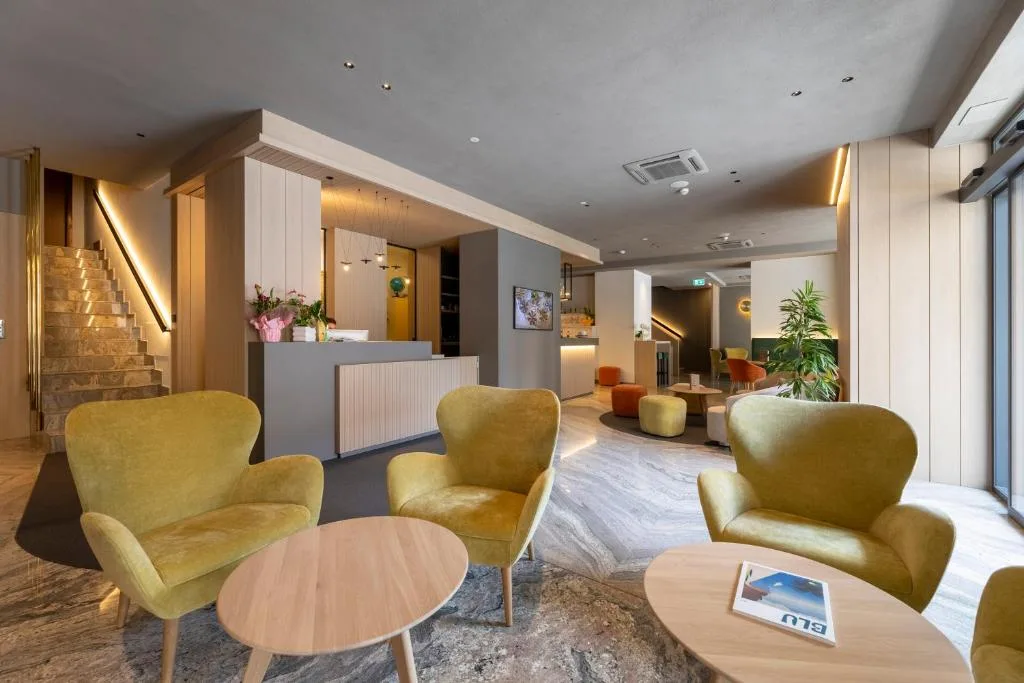 Lounge moderna con poltrone gialle, reception e pavimento in marmo