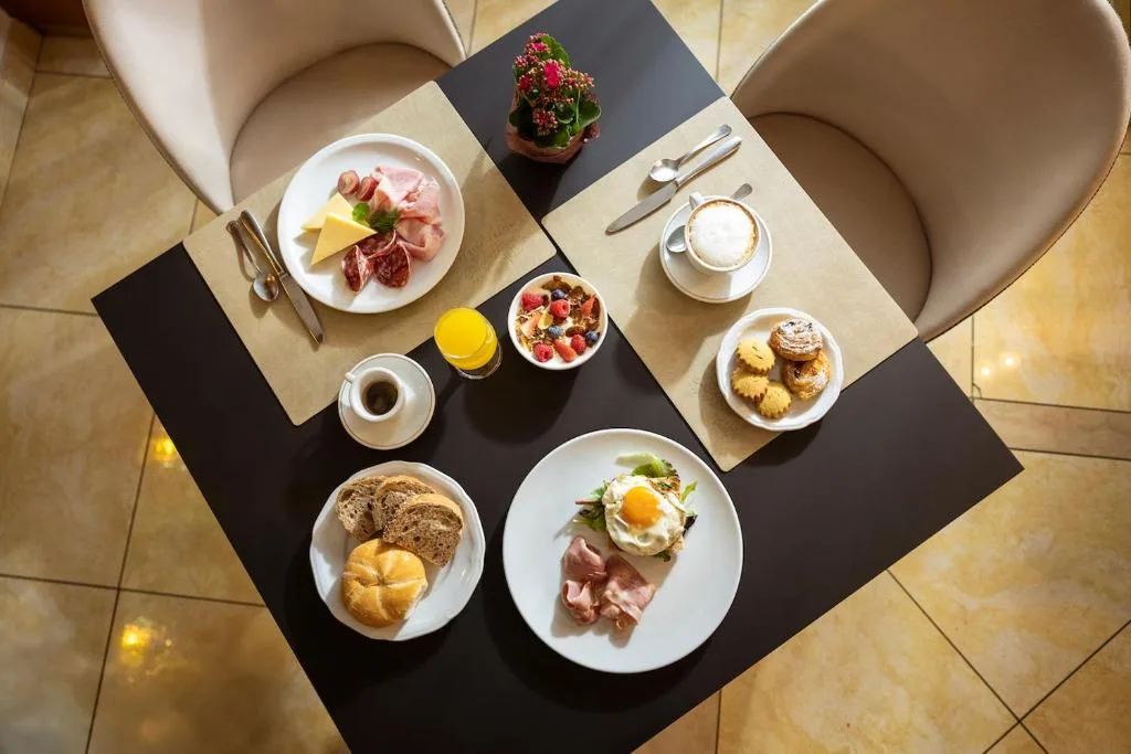 Tavolo colazione vista dall'alto con affettati, dolci, caffè e uova