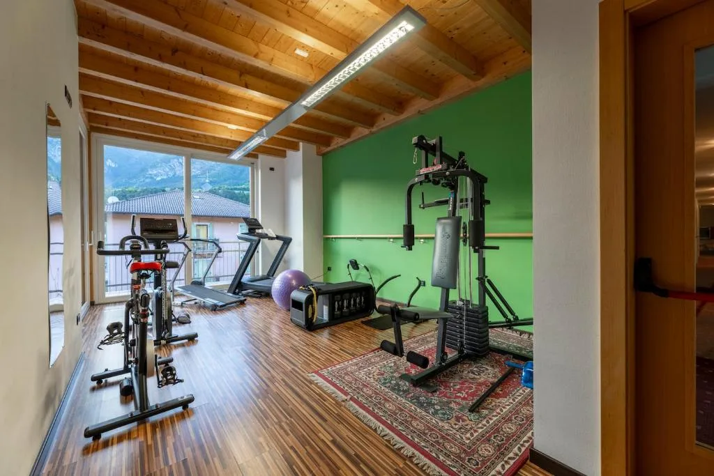 Palestra con attrezzi cardio, parete verde e vista sulle montagne