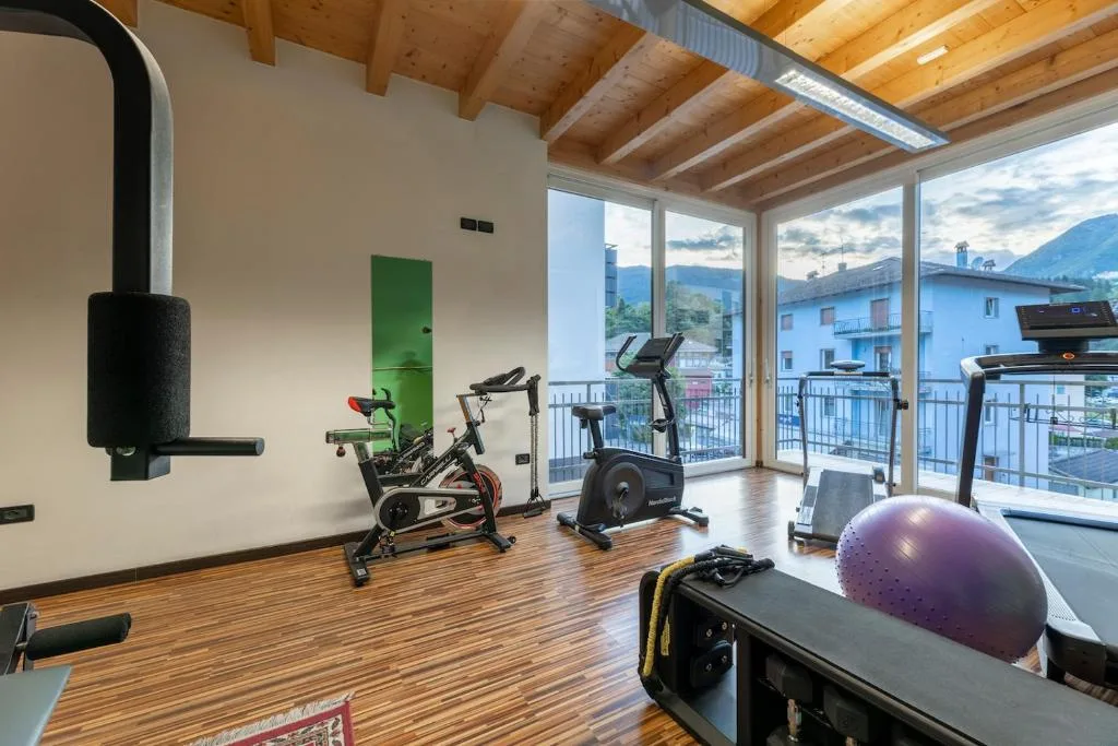 Sala fitness con cyclette, tapis roulant e ampie vetrate sul paese