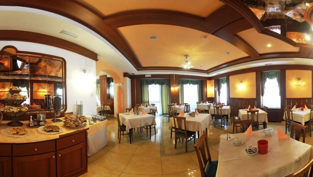 Sala colazione con buffet di dolci, tavoli apparecchiati e soffitto in legno