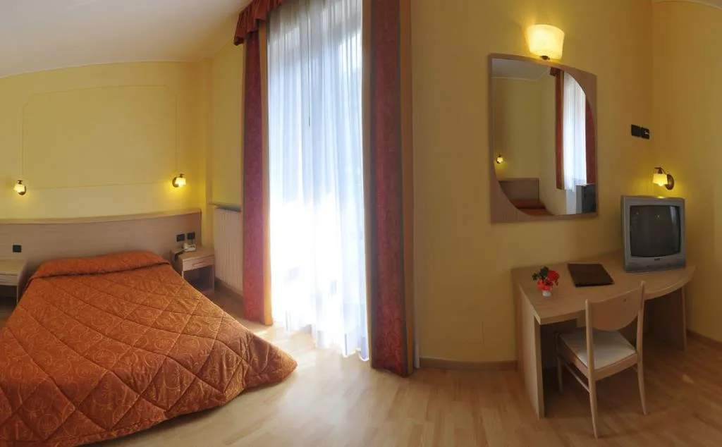 Camera con letto matrimoniale, copriletto arancione, scrivania e TV