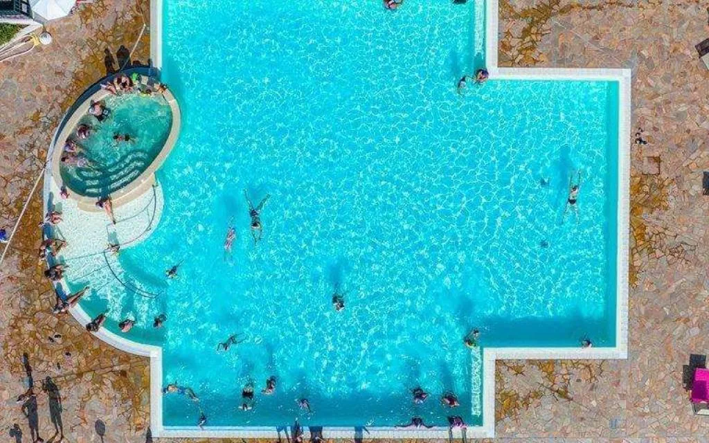 Vista aerea della grande piscina a forma di croce con bagnanti