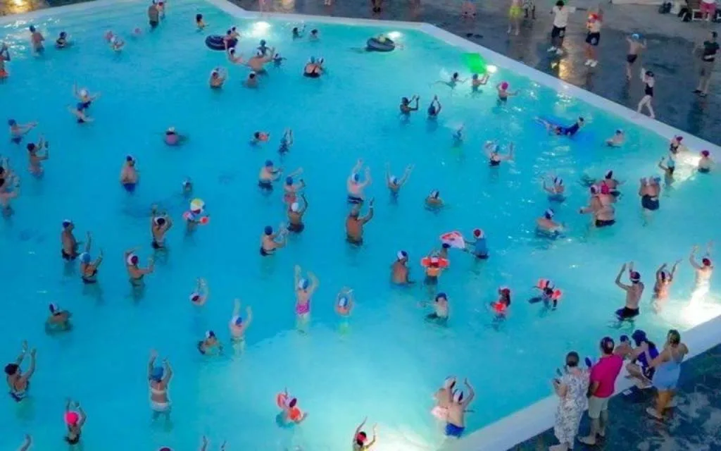 Lezione di acquagym in piscina con numerosi partecipanti