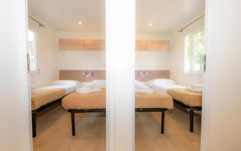 Camere con letti singoli e mobili in legno chiaro in mobile home