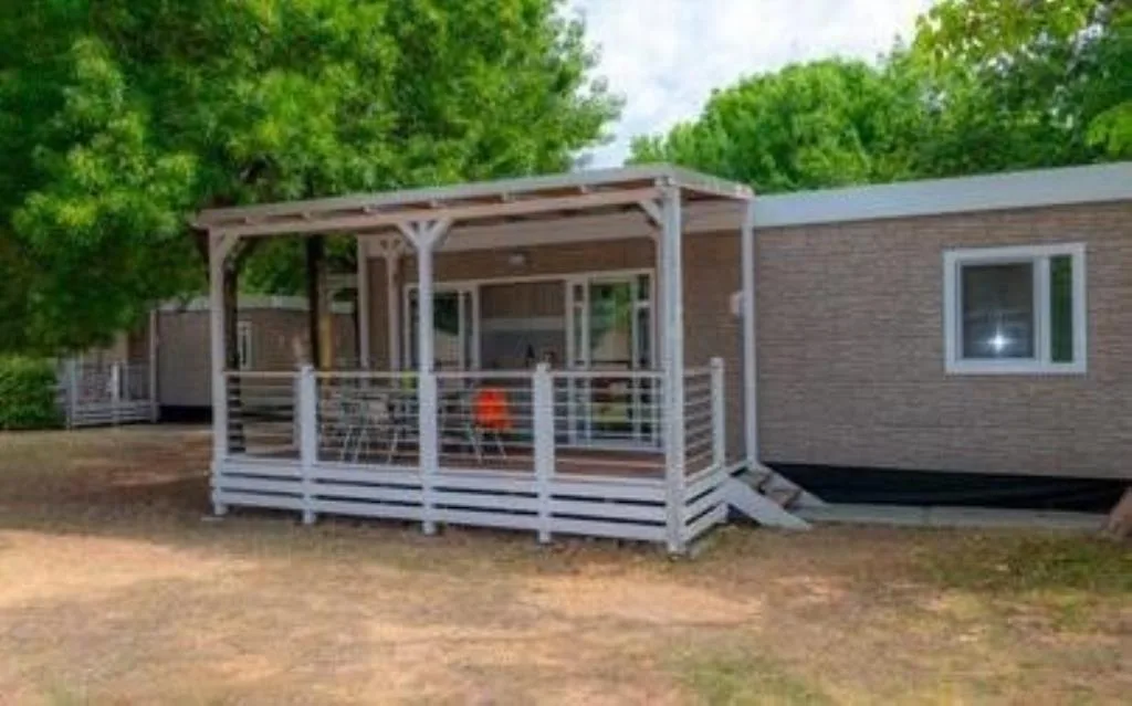Mobile home moderna con ampia veranda coperta immersa nel verde