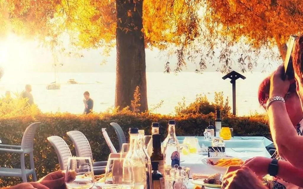 Tavolo apparecchiato all'aperto con vista sul lago al tramonto